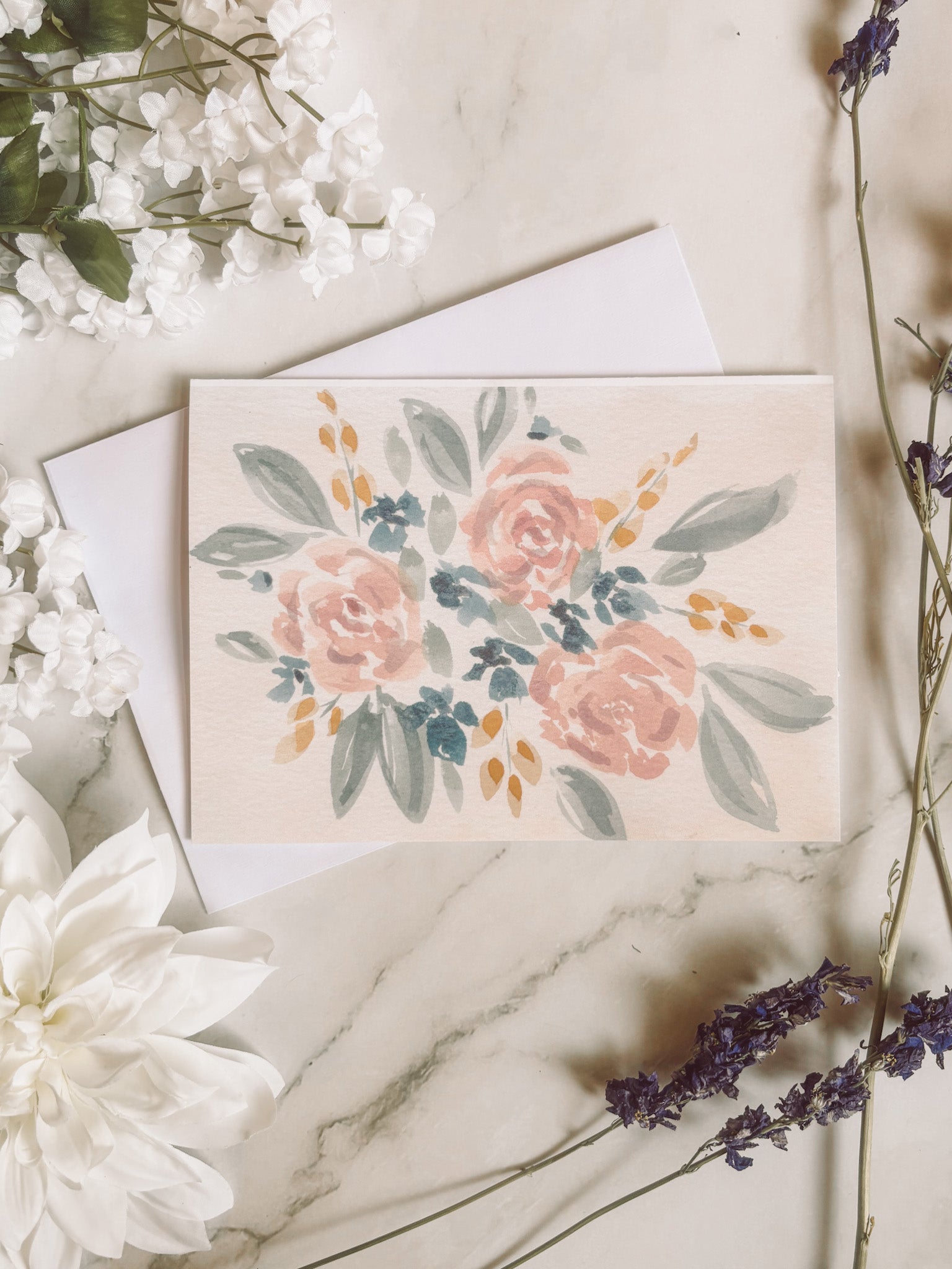 Floral card with envelope on a marble surface surrounded by flowers