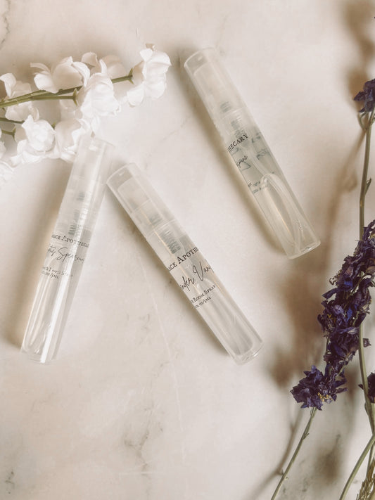Clear glass bottles with labels on a marble surface with flowers and lavender.