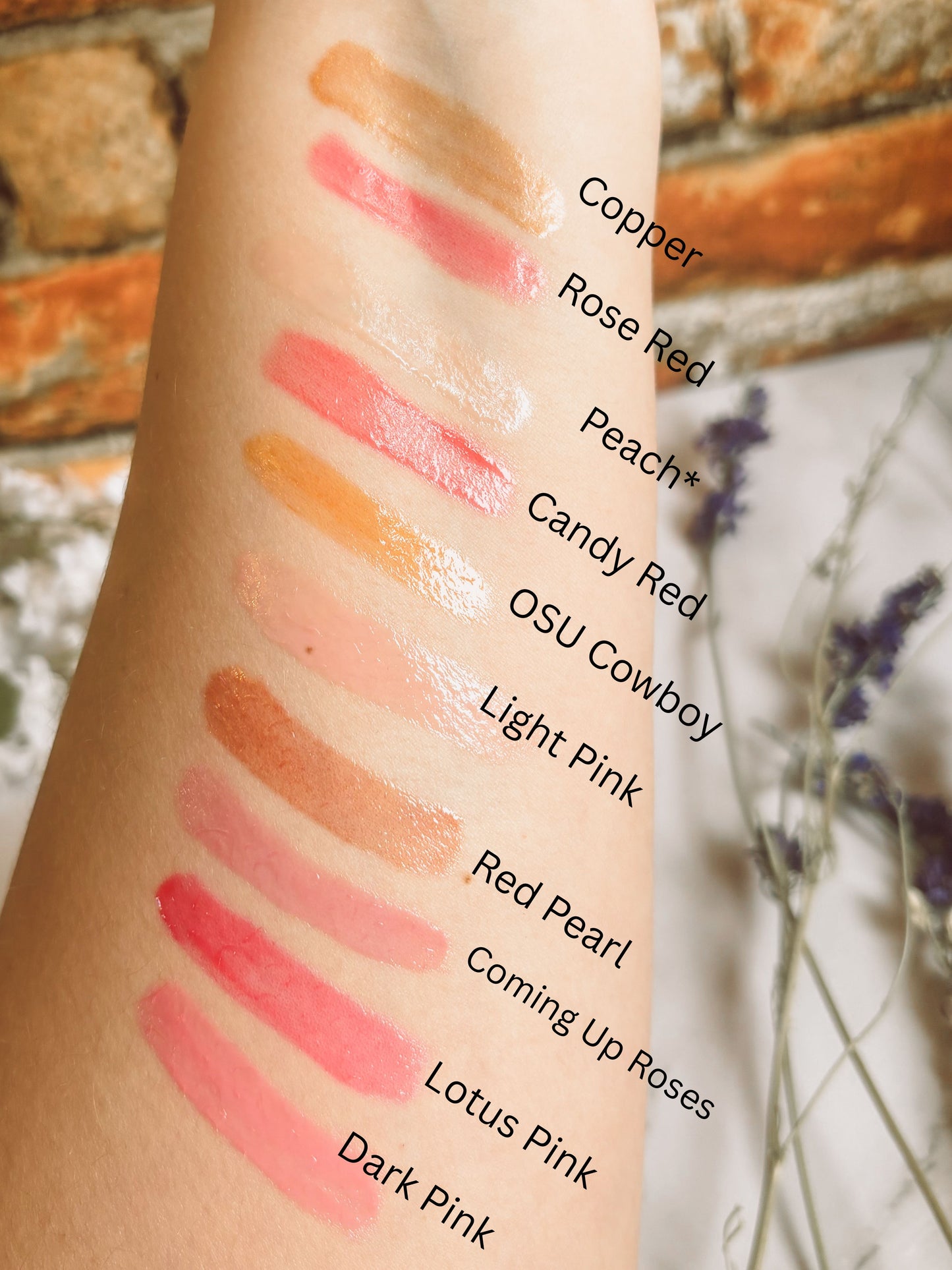 Lipstick swatches on a person's arm with color names labeled against a natural background.
