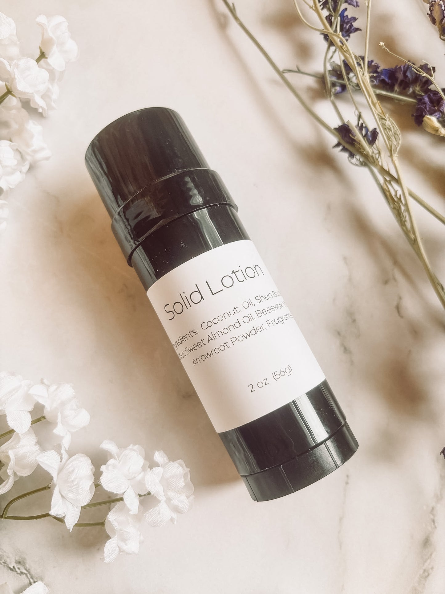 Solid lotion bar with black container and white label on a light background with flowers.